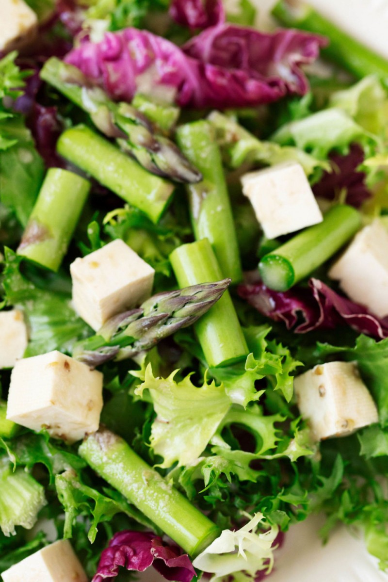 A zoomed in, overhead shot of a springtime salad that's been piled with herbed tofu feta cheese. 