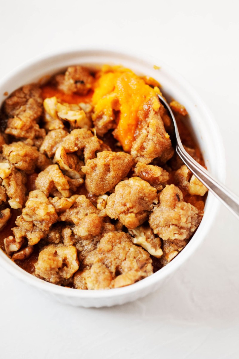 A small, circular baking dish is filled with a miniature version of vegan sweet potato casserole.