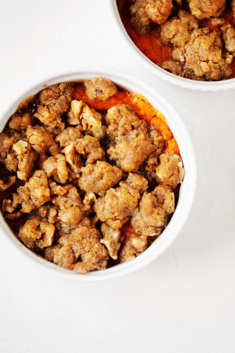 Two small, circular baking dishes, filled with a festive plant-based sweet potato dish.