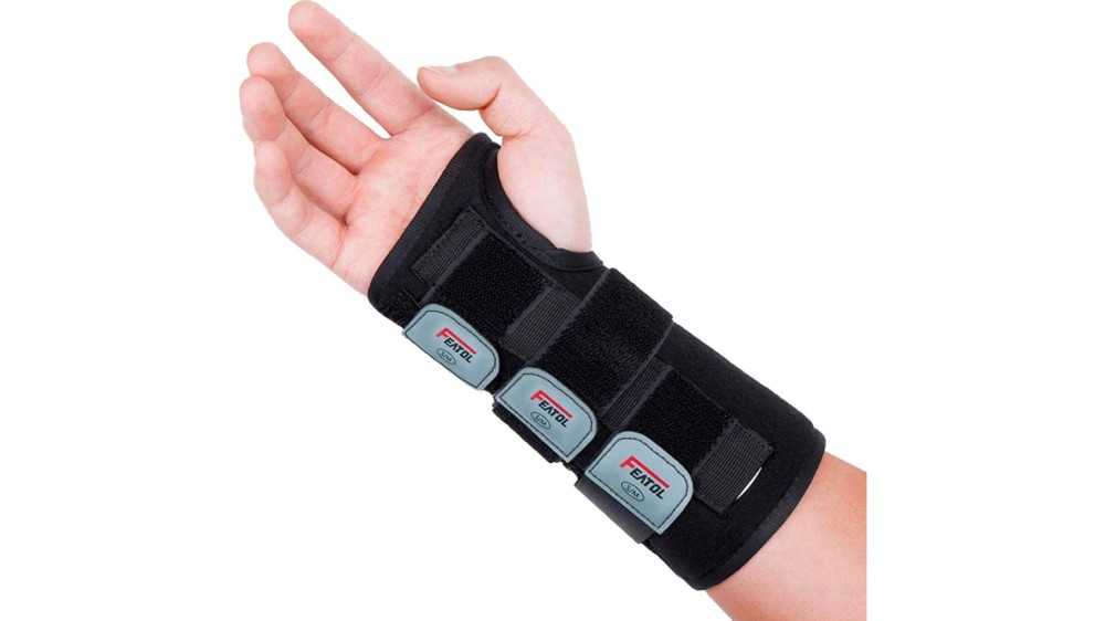 A hand wearing a black wrist brace that wraps around the thumb and extends town the forearm.