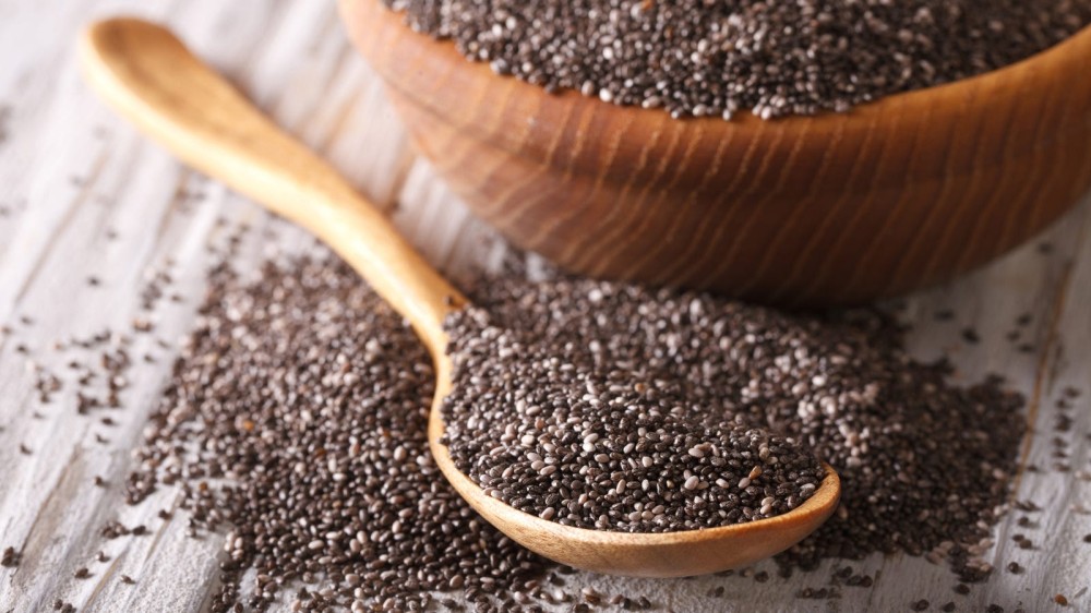 A bowl and a spoon full of chia seeds overflowing onto the counter.