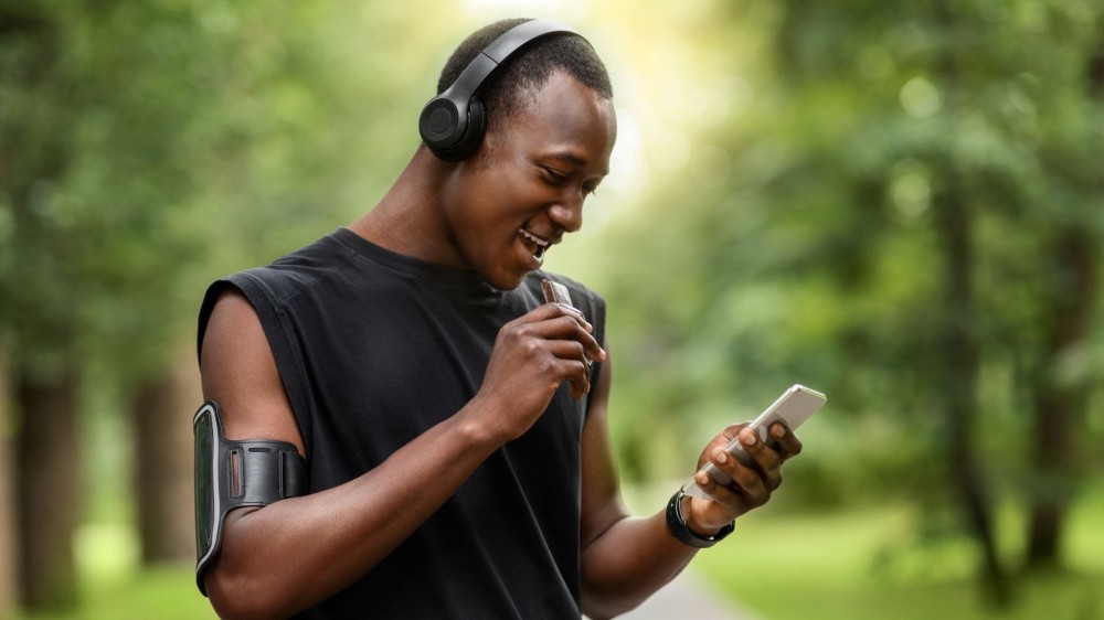 Man eating a protein bar and looking at his phone.