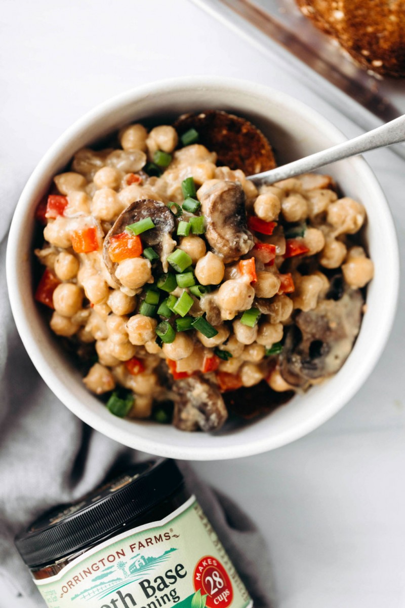 An overhead image of a bean dish, with a gray napkin and a container of bouillon powder nearby.