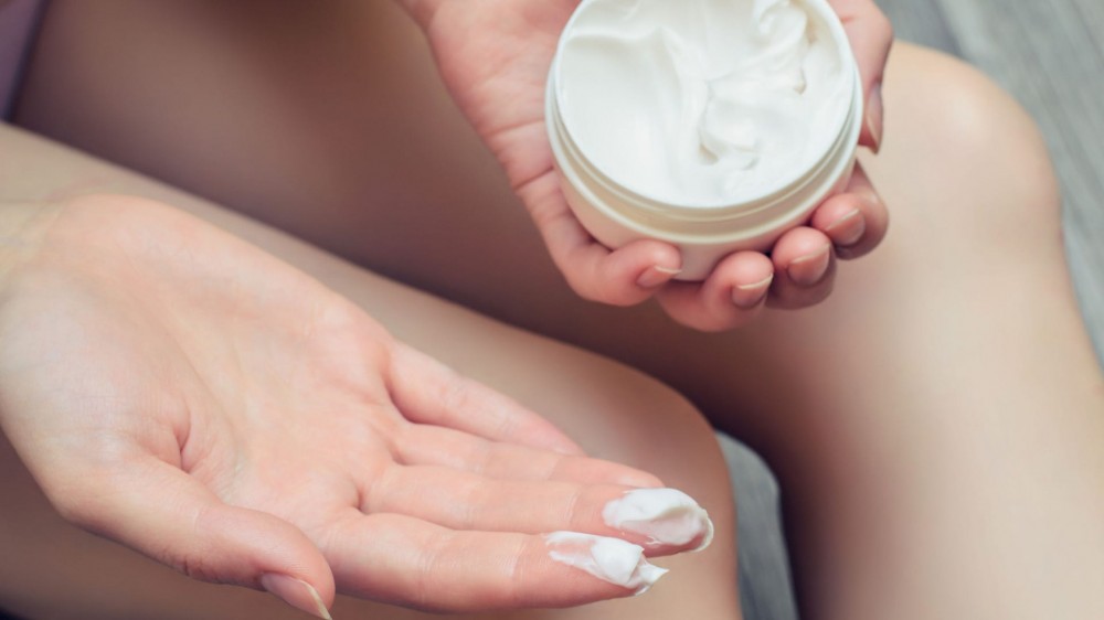 Close up photo of woman applying moisturizing cream on her body.