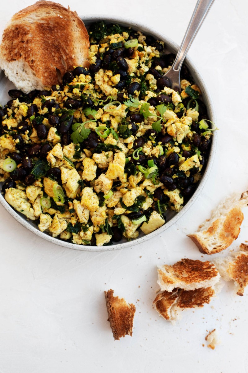 A large, round serving dish holds a savory vegan breakfast.