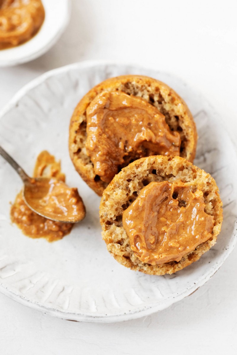 A close up shot of a vegan banana snack muffin, topped with some chunky peanut butter.