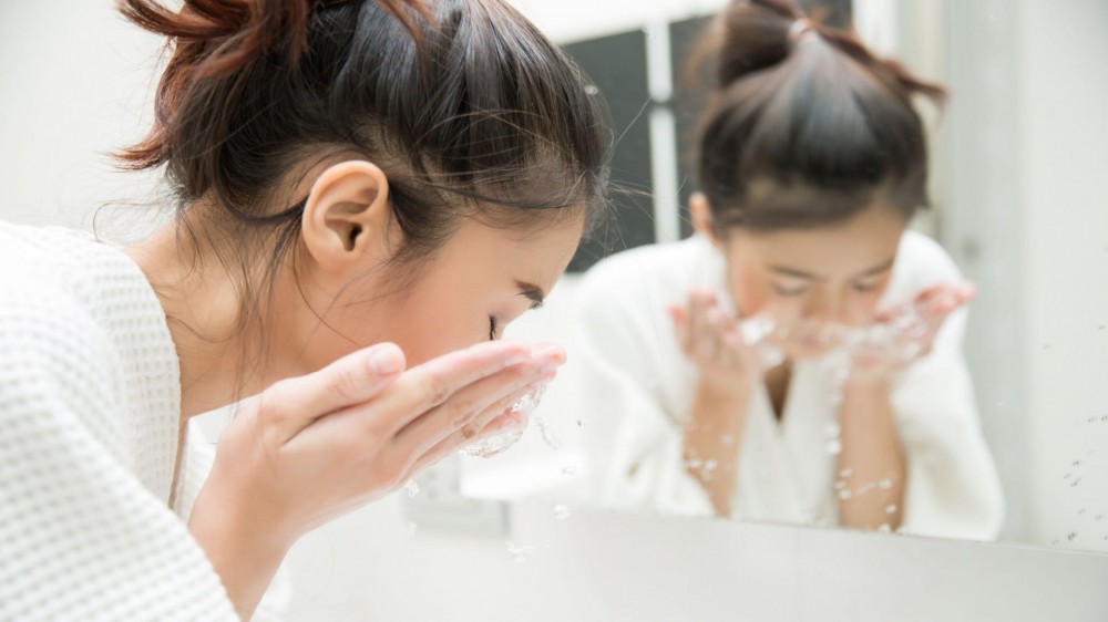 A woman washes her face