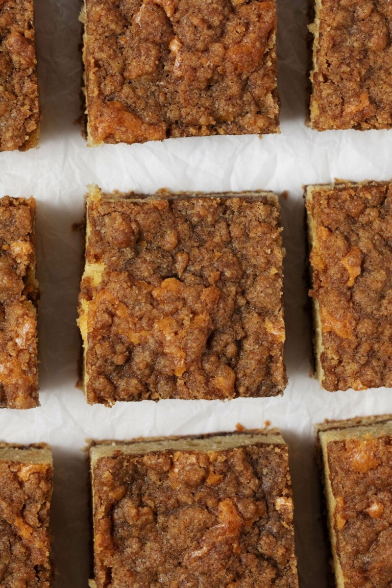 Vegan slices of sour cream coffee cake are arranged on a piece of white parchment.