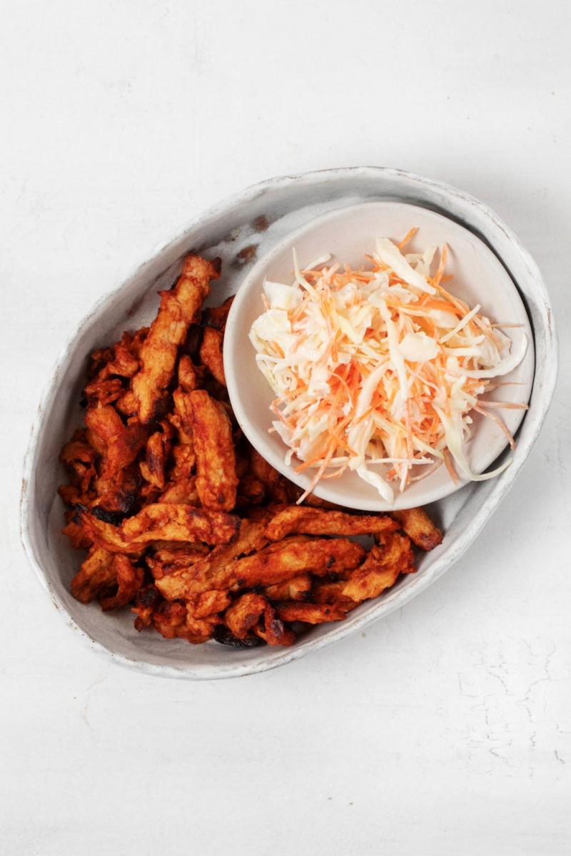 A vegan protein is being served on a small, oval platter with coleslaw.