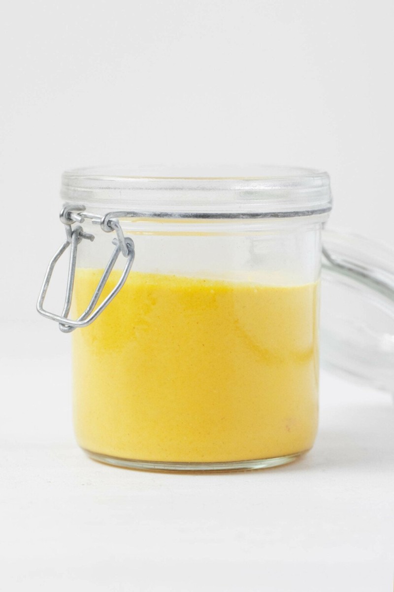 A sideways image of a mason jar, which has been filled with an electric gold, creamy sauce.